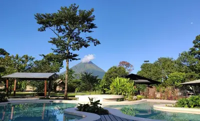 a swimming pool with a mountain in the background at Hotel Arenal Glamping in Fortuna