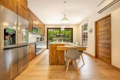 a kitchen with wooden cabinets and a wooden table at Casa Coralis - Stunning modern 3 BR, 3-half bath home in Playa Potrero in Potrero