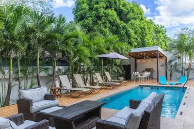 a pool with chairs and a table and trees at Casa Coralis - Stunning modern 3 BR, 3-half bath home in Playa Potrero in Potrero