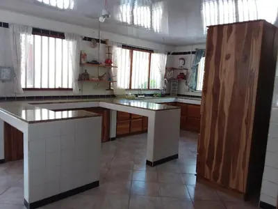 a kitchen with white counter tops and wooden cabinets at Maison du Bonheur CABALLO DEL MAR sur la plage avec bassin de rafraichissement in Parrita