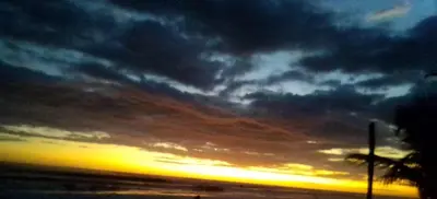 a cloudy sky at sunset with a palm tree at Maison du Bonheur CABALLO DEL MAR sur la plage avec bassin de rafraichissement in Parrita