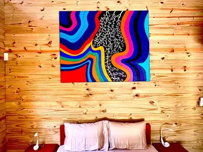 a painting hanging on a wooden wall above a bed at Ocean Melody 4 in Uvita