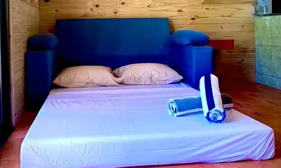 a white bed with a blue headboard and a bag on it at Ocean Melody 4 in Uvita
