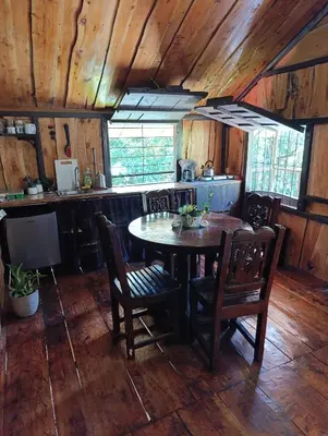 a kitchen with a table and chairs in a room at Cabaña de montaña Queca in Poás