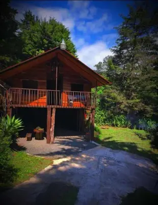 a house with a balcony and a porch at Cabaña de montaña Queca in Poás
