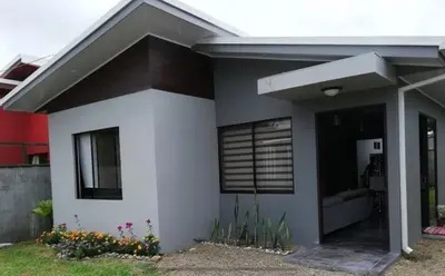 a white house with a window and some flowers at Casa Laureles in Guápiles