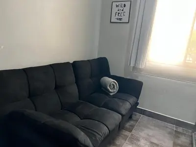 a black couch in a living room with a window at Casa Laureles in Guápiles