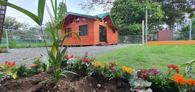 a small wooden house with flowers in a garden at Cabaña Tio King in Uvita