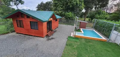 a small house with a pool next to a fence at Cabaña Tio King in Uvita