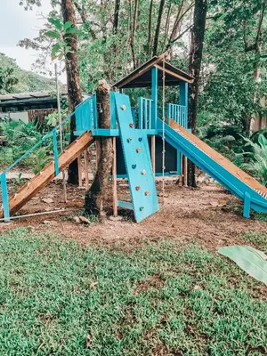 a playground with a blue slide next to a tree at Little Escape in Santa Teresa Beach