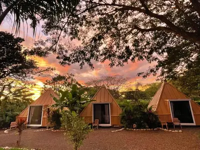 a group of tents with a sunset in the background at Pyramid Tamarindo Luxury Hotel in Tamarindo