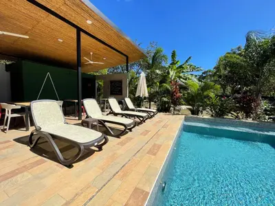 a group of chairs sitting next to a swimming pool at Pyramid Tamarindo Luxury Hotel in Tamarindo