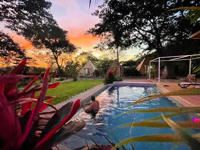 a man in a swimming pool in a backyard at Pyramid Tamarindo Luxury Hotel in Tamarindo