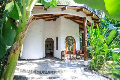 a house with a porch with a table and chairs at Manala Hotel in Santa Teresa Beach