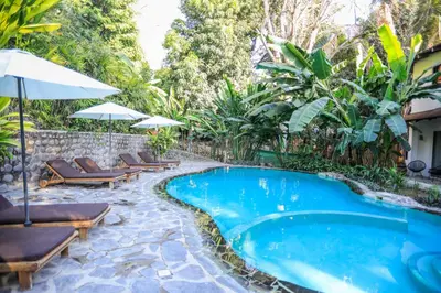 a pool with chairs and umbrellas in a garden at Manala Hotel in Santa Teresa Beach