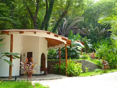 a small house with a roof in a garden at Manala Hotel in Santa Teresa Beach
