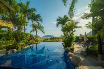 a swimming pool in a resort with palm trees at Vista Bahia 3D 3 bdr Ocean View in Los Suenos in Herradura
