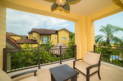 a balcony with a chair and a view of a house at Vista Bahia 3D 3 bdr Ocean View in Los Suenos in Herradura