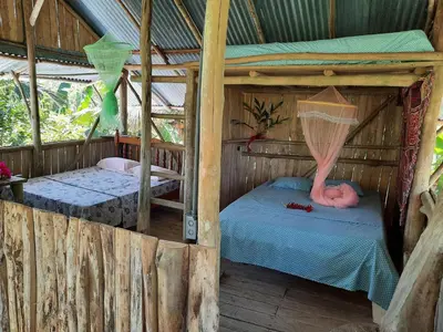a bedroom with two beds in a wooden house at La Muñequita Lodge 2 - culture & nature experience in Palmar Sur