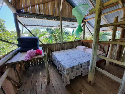 a bed in a room in a wooden house at La Muñequita Lodge 2 - culture & nature experience in Palmar Sur