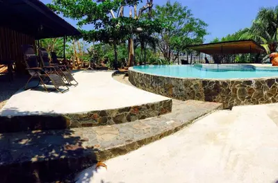 a swimming pool with two chairs and a table at Beautiful Second Story Apartment 202 Next to Playa Flamingo in Playa Flamingo