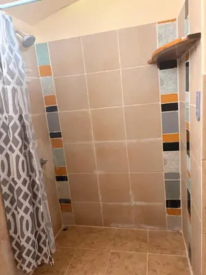 a shower in a bathroom with a tiled wall at Beautiful Second Story Apartment 202 Next to Playa Flamingo in Playa Flamingo