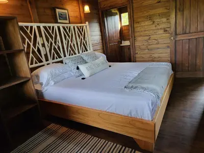 a large bed in a room with wooden walls at Jaco-Carara 3 bdrm surrounded by rainforest with private pool in Carara