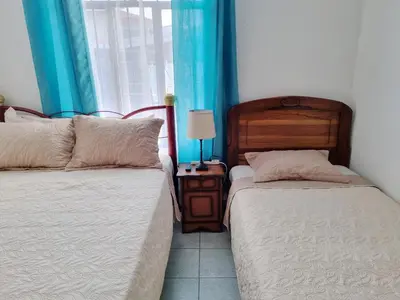 two beds in a room with blue curtains at Entire Cozy apartment for you, 5 min SJO Airport in Alajuela City