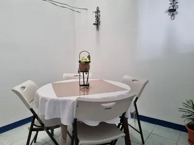 a table with white chairs and a basket of flowers on it at Entire Cozy apartment for you, 5 min SJO Airport in Alajuela City
