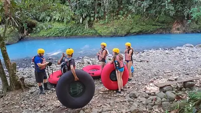 a group of people standing next to a river with rafts at Hotel Rio Celeste to Know in Rio Celeste