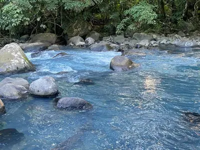 a river with rocks in the middle of it at Hospedaje Rio Celeste Katira, Habitación privada in San Rafael
