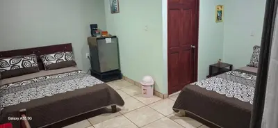 a bedroom with two beds and a refrigerator at Hospedaje Rio Celeste Katira, Habitación privada in San Rafael