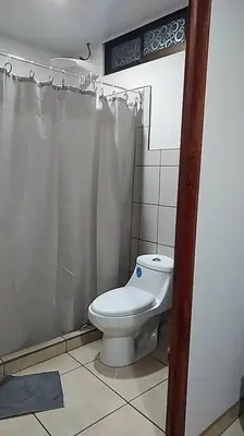 a bathroom with a white toilet and a shower at Hospedaje Rio Celeste Katira, Habitación privada in San Rafael