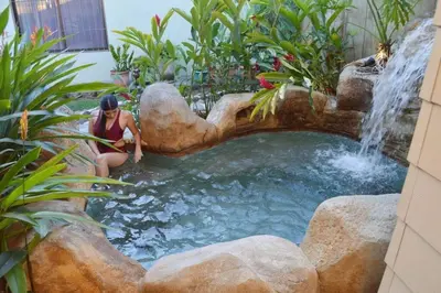 a woman sitting next to a waterfall in a garden at Elegant Villa in La Fortuna with spacious backyard plus very private pool & parking in Fortuna