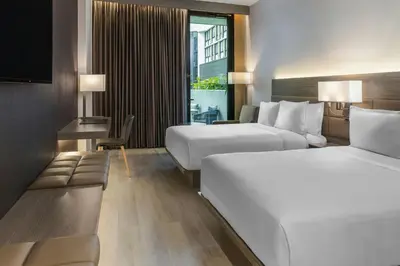a hotel room with two beds and a table at AC Hotel San Jose Airport Belen in San José