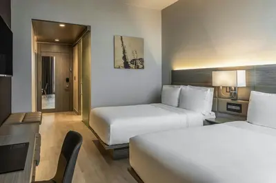 a hotel room with two beds and a desk at AC Hotel San Jose Airport Belen in San José