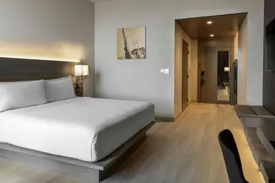 a bedroom with a large white bed and a hallway at AC Hotel San Jose Airport Belen in San José