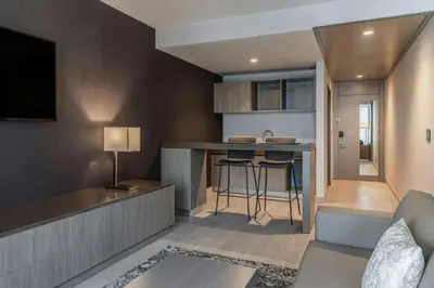 a living room with a couch and a kitchen at AC Hotel San Jose Airport Belen in San José