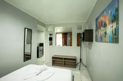 a white room with a bed and some paintings at Coati Arenal Lodge in Fortuna