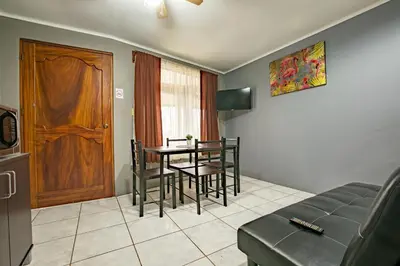a living room with a table and chairs and a door at Coati Arenal Lodge in Fortuna