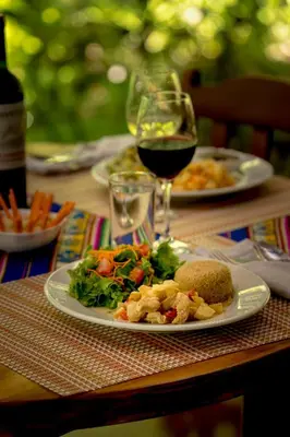 a table with two plates of food and a glass of wine at Ocean Forest Ecolodge in San Pedrillo