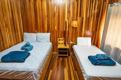 two beds in a room with wooden walls at Cowboy Hostel - Habitaciones con Baño Privado in Monteverde Costa Rica
