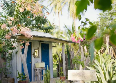a small house with a blue door in a garden at La Caravana in Sámara