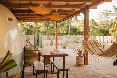 a patio with a hammock and a table and chairs at La Caravana in Sámara