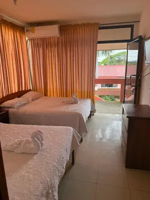 a hotel room with two beds and a window at Hotel La Roca del Mar in Puntarenas