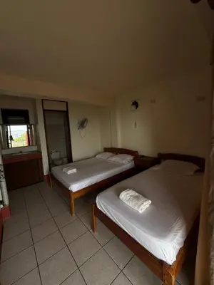 two twin beds in a room with a window at Hotel La Roca del Mar in Puntarenas