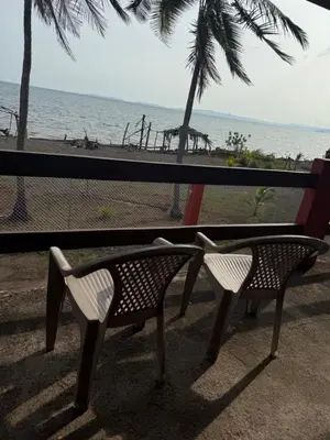 two benches sitting on the beach near the ocean at Hotel La Roca del Mar in Puntarenas