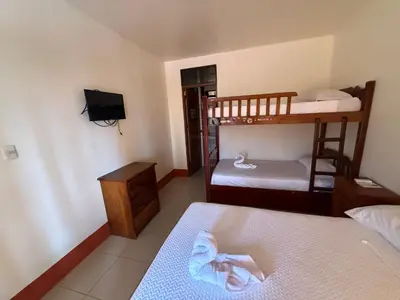 a small room with two bunk beds and a television at Hotel La Roca del Mar in Puntarenas