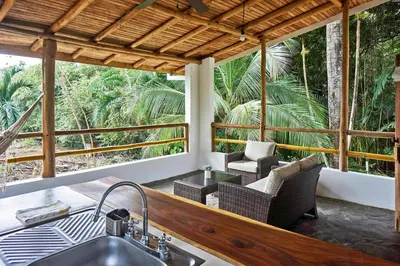 a kitchen with a sink and chairs on a porch at Villa Ananda in Mal País