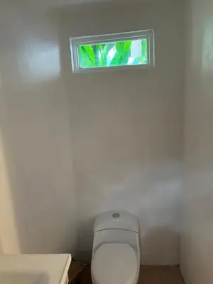 a bathroom with a toilet and a window at Pura Vida Hostel in Tamarindo